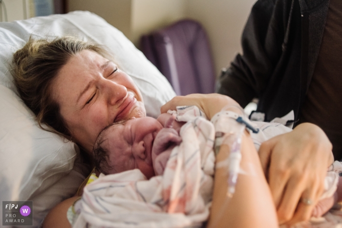 A mother gets emotional as she holds her newborn in the hospital for the first time in this birth photo composed by an award-winning Philadelphia photographer.