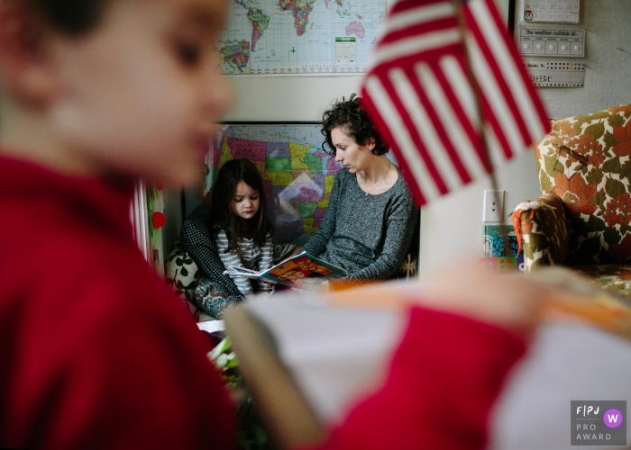 A mother reads a book to her daughter while her son plays nearby in this photo by a Philadelphia award-winning family photographer. 