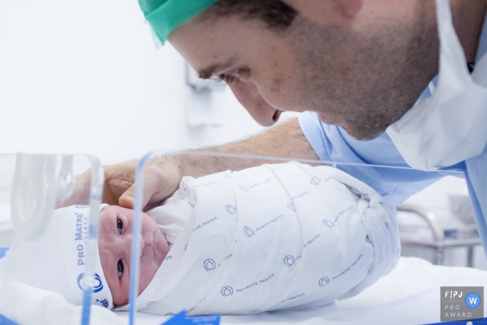 A father visits his newborn infant in the hospital in this award-winning image captured by a Sao Paulo, Brazil birth photographer.