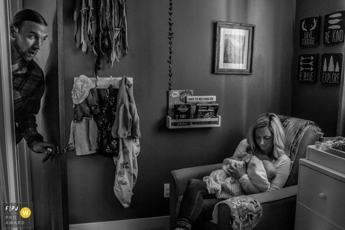 A father checks in on his wife as she holds their sleeping baby in this family picture by a Boulder, CO photographer. 