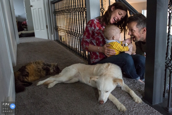 Une mère et un père jouent avec leur bébé tandis que leur chien et leur chat gisent à côté d'eux sur cette photo réalisée par un photographe de famille documentaire de Boulder, CO.