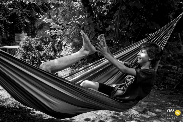 Photo by: <a href="https://www.fpja.com/documentary-family-photography-contests/sybil-rondeau/nantes/2099764">Sybil Rondeau - France</a> Nantes black and white family photography of a father and son playing in a hammock