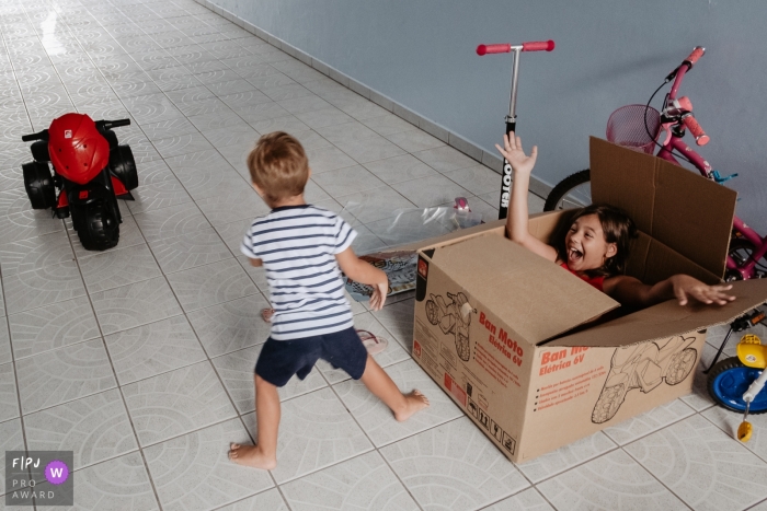 Photo by: <a href="https://www.fpja.com/documentary-family-photography-contests/thiago-braga/florianopolis/2099892">Thiago Braga - Brazil</a> Brazil Child and Family Photographer | Brothers playing at home. Boy after receiving a birthday present, is surprised by his sister who hides inside the toy box.