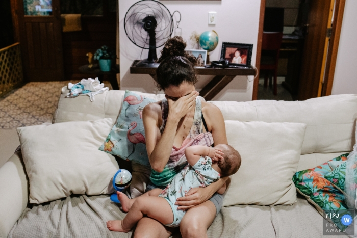 Photo by: <a href="https://www.fpja.com/documentary-family-photography-contests/thiago-braga/florianopolis/2099898">Thiago Braga - Brazil</a> Florianopolis Day in the Life Photographer | tired mother, after her daily routine, breastfeeds her baby girl and demonstrates the normal tiredness of a family end of day