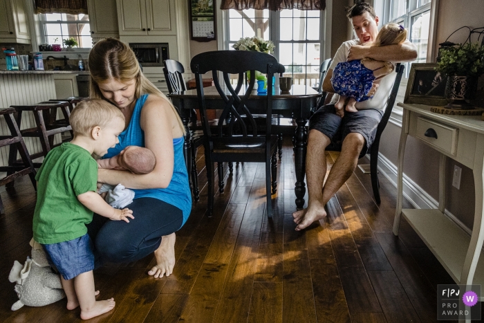 Ontario family photojournalism | A boy opens mouth to kiss baby while father does the same to girl in Canada