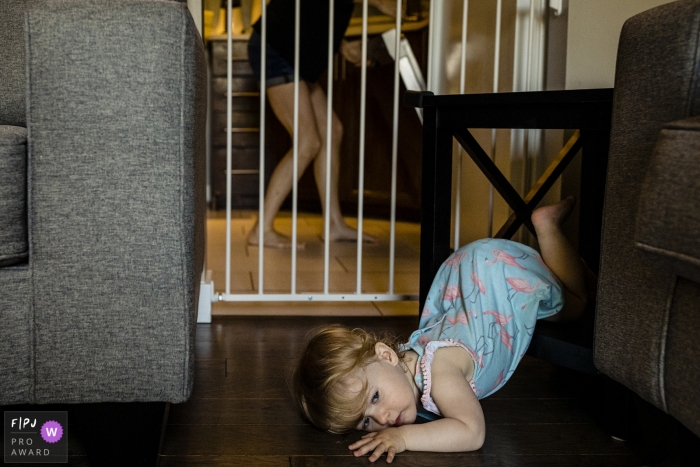 Ontario family photography in Canada - Photo session - toddler lies on floor with legs tangled in table 