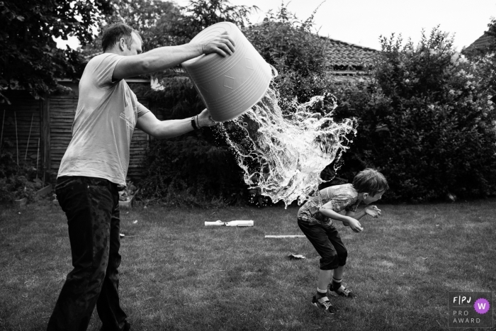 Photojournalisme familial du Cambridgeshire en Angleterre dans l'arrière-cour lors d'une bataille d'eau entre père et fils.