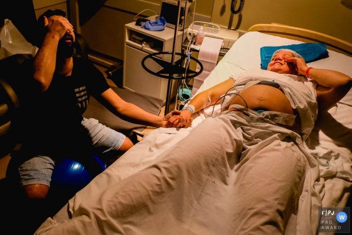 Photo by: <a href="https://www.fpja.com/documentary-family-photography-contests/renato-mello/rio-grande-do-sul/2100497">Renato Mello - Brazil</a> Rio Grande do Sul, Brazil hospital birthing photography session showing mom and dad feeling tired.