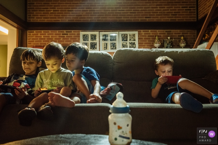 Photo by: <a href="https://www.fpja.com/documentary-family-photography-contests/claudia-ruiz/rio-de-janeiro/2100564">Claudia Ruiz - Brazil</a> Rio de Janeiro Family and Kids Photography | 4 children on a sofa distracted on cellphones