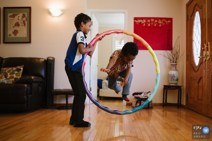 Photo by: <a href="https://www.fpja.com/documentary-family-photography-contests/tiffany-luong/los-angeles/2100594">Tiffany Luong - United States</a> Los Angeles brothers jumping through hula hoop at home during this California family photo session.
