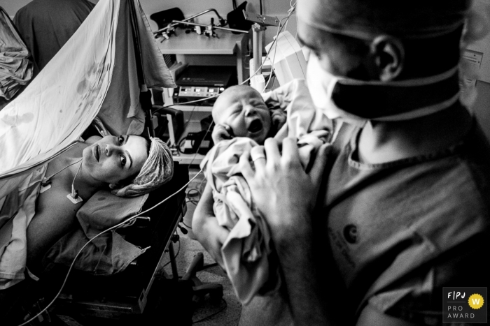 Photos en noir et blanc du Rio Grande do Sul de l'accouchement à l'hôpital au Brésil - un père tenant un nouveau-né