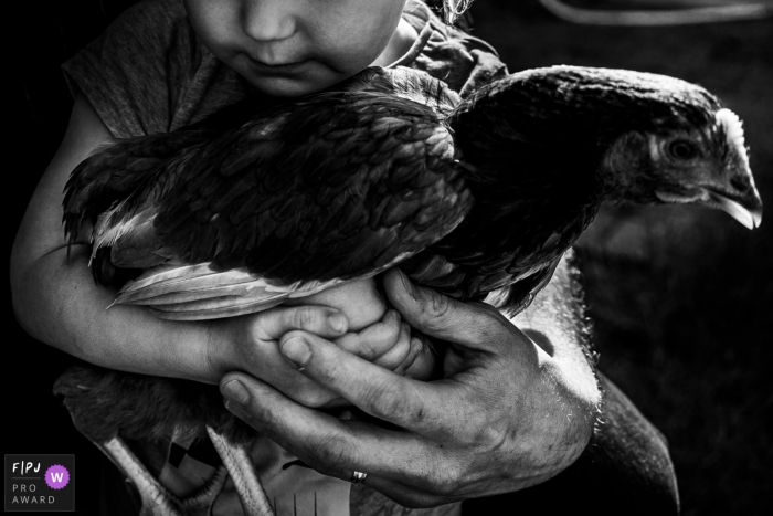 Photo by: <a href="https://www.fpja.com/documentary-family-photography-contests/linda-mauch/kent/2101120">Linda Mauch - United Kingdom</a> Kent family photography for all of England - Girl holding chicken