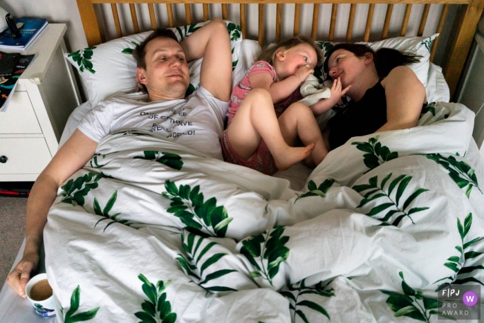 Photo by: <a href="https://www.fpja.com/documentary-family-photography-contests/linda-mauch/kent/2101135">Linda Mauch - United Kingdom</a> Kent England family photo session with Mum, Dad and daughter in bed
