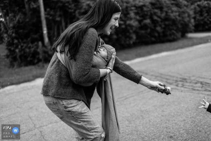 Photo by: <a href="https://www.fpja.com/documentary-family-photography-contests/viara-mileva/kingston/2101273">Viara Mileva - Canada</a> Mom holds baby and hands toy to other child | Family Photography Session in ON, Canada