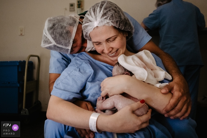 Photo by: <a href="https://www.fpja.com/documentary-family-photography-contests/thiago-braga/florianopolis/2101384">Thiago Braga - Brazil</a> Santa Catarina birth photographer. Excited father and mother hugging their newly born daughter.