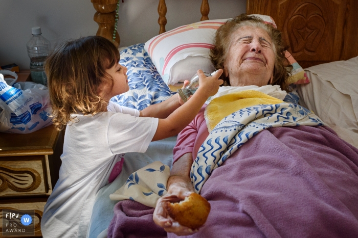 Photo by: <a href="https://www.fpja.com/documentary-family-photography-contests/emanuelle-rigoni/recife/2101420">Emanuelle Rigoni - Brazil</a> Pernambuco granddaughter playing with her sick grandmother | Recife family photography of kids