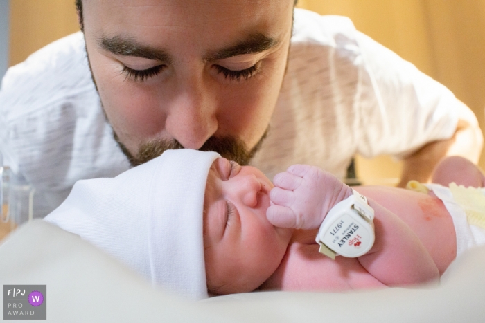 Photo by: <a href="https://www.fpja.com/documentary-family-photography-contests/cibele-piovesan/sao-paulo/2101439">Cibele Piovesan - Brazil</a> Sao Paulo dad kisses newborn baby in the hospital - Brazil birth photography