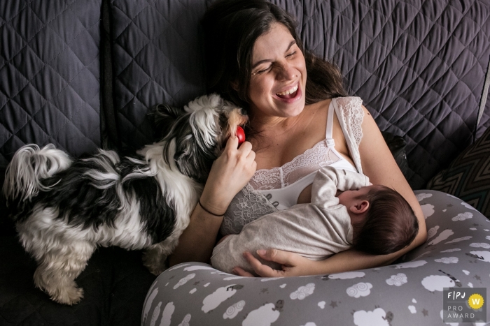 Photo by: <a href="https://www.fpja.com/documentary-family-photography-contests/adriana-costa/belo-horizonte/2101490">Adriana Costa - Brazil</a> Minas Gerais woman has fun with her dog while breastfeeding her newborn baby - Family photography of newborns in Brazil.