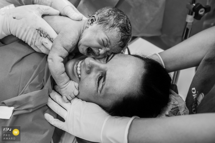 Bébé pleure et il est placé sur le visage de sa mère après la naissance par césarienne | Photographie de naissance RJ