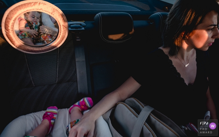 Photo by: <a href="https://www.fpja.com/documentary-family-photography-contests/lisandro-castro/cuiab%C3%A1/2101531">Lisandro Castro - Brazil</a> Cuiabá mom riding in the backseat of a car with her baby. - Brazil family photography.