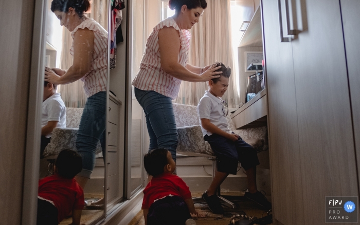Photo by: <a href="https://www.fpja.com/documentary-family-photography-contests/lisandro-castro/cuiab%C3%A1/2101534">Lisandro Castro - Brazil</a> Mato Grosso boy having his hair done by mom with brother looking on - Brazil family picture shooting session.