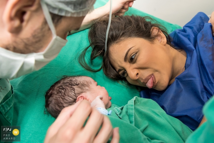 Photo by: <a href="https://www.fpja.com/documentary-family-photography-contests/alessandra-corveloni/rio-de-janeiro/2101539">Alessandra Corveloni - Brazil</a> Mother sticks her tongue out at her newborn baby as they look eyes with one another | Rio de Janeiro Birthing Photography