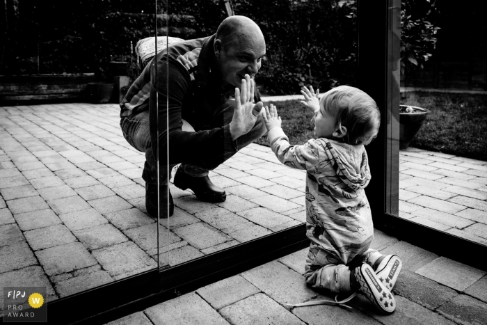 Photo by: <a href="https://www.fpja.com/documentary-family-photography-contests/annemiek-kinneging/drenthe/2101583">Annemiek Kinneging - Netherlands</a> Father and son play with glass doors separating them | Drenthe Family Photography
