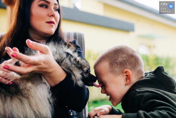 Photo by: <a href="https://www.fpja.com/documentary-family-photography-contests/polona-avanzo/ljubljana/2101605">Polona Avanzo - Slovenia</a> Dog kisses a young boy's face with a nice lick of his tongue | Slovenia Family Photographer
