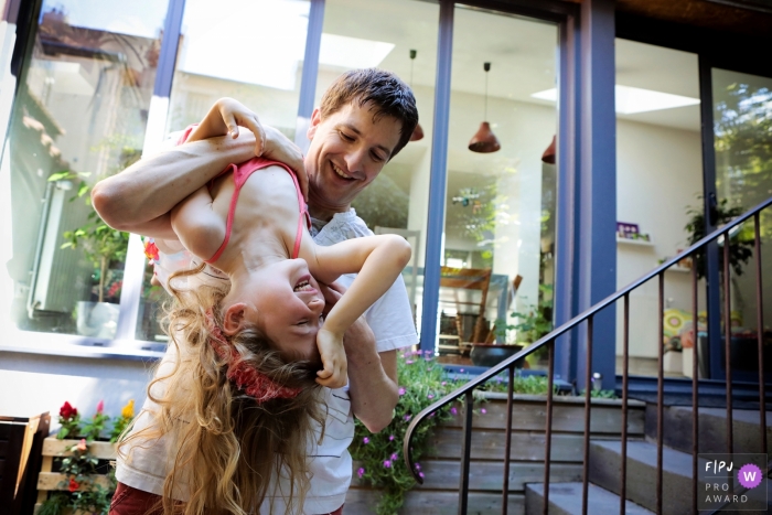 Photo by: <a href="https://www.fpja.com/documentary-family-photography-contests/elodie-chabrier/allier/2101633">Elodie Chabrier - France</a> Allier family photo session with dad and daughter outside on the porch having fun.