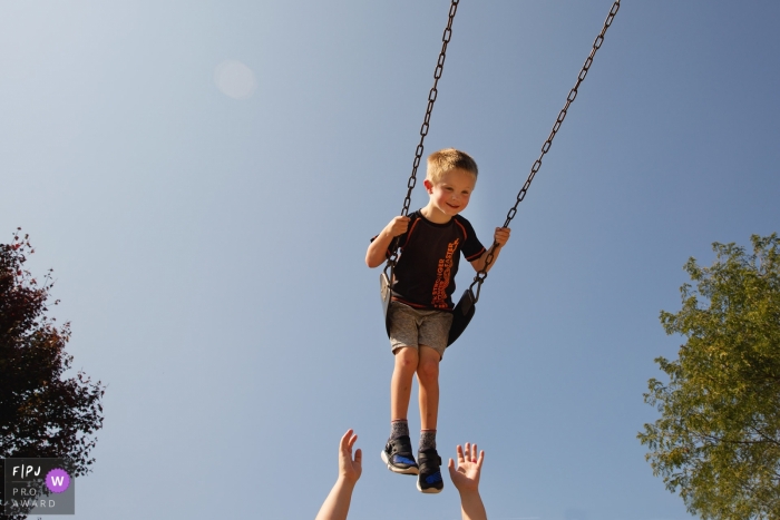 Photo by: <a href="https://www.fpja.com/documentary-family-photography-contests/amber-roy/state-college/2101680">Amber Roy - United States</a> State College Pennsylvania boy in a swing - PA family photo session outside at the park.
