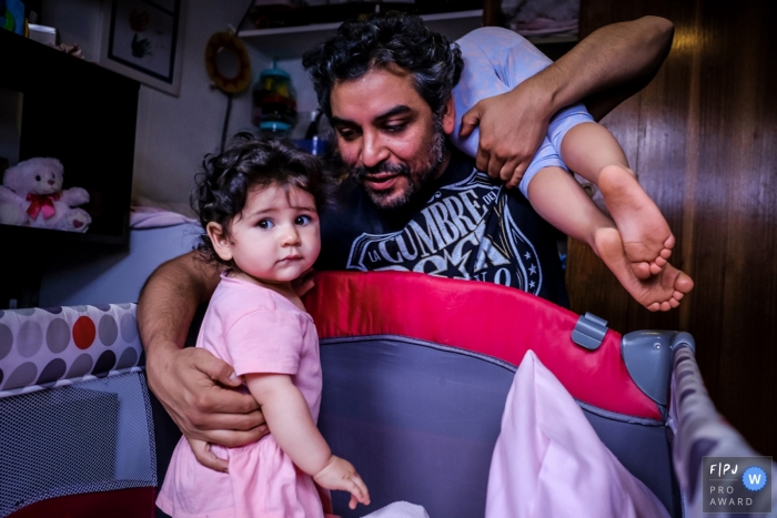 Photo by: <a href="https://www.fpja.com/documentary-family-photography-contests/alvaro-tejeda/talca/2101711">Alvaro Tejeda - Chile</a> Taica Family Photographer | Father comforting young girl in her pack-and-play