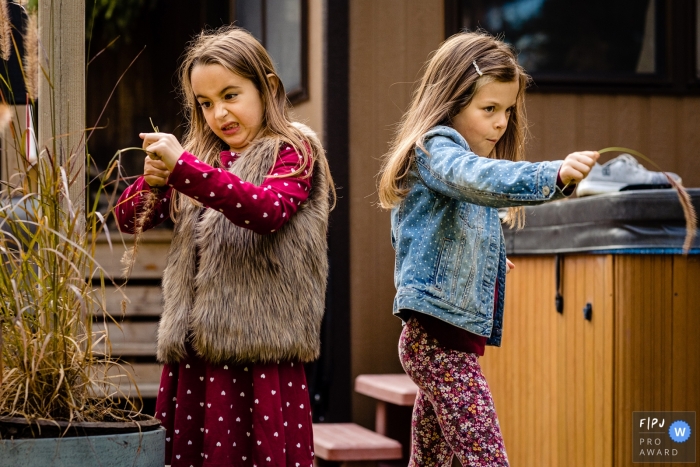 Canada girls make faces while playing with grass during an Ontario family photography shoot at home.