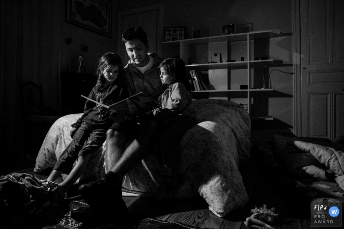 Photo by: <a href="https://www.fpja.com/documentary-family-photography-contests/marine-poron/paris/2101860">Marine Poron - France</a> Father reads his children an evening story | Paris Family Photographer