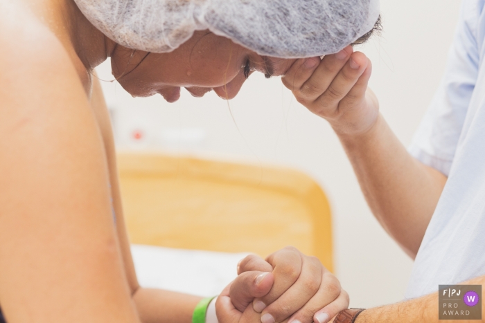 Photo by: <a href="https://www.fpja.com/documentary-family-photography-contests/ana-paula-faria/sao-paulo/2101866">Ana Paula Faria - Brazil</a> Woman clutches hands with her partner during labor | Sao Paulo Birthing Photography