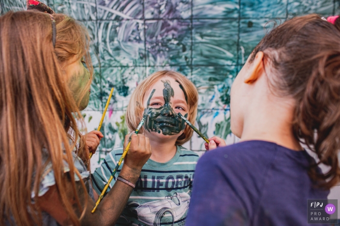 A boy gets his face painted up by two girls | Sao Paulo child photography