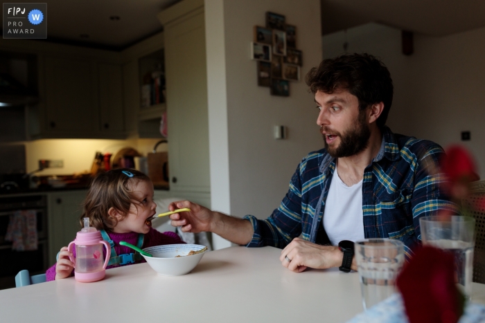 Photo by: <a href="https://www.fpja.com/documentary-family-photography-contests/catherine-hill/kent/2101989">Catherine Hill - United Kingdom</a> Kent father gives his daughter some encouragement at tea time - In home family photography sessions for England