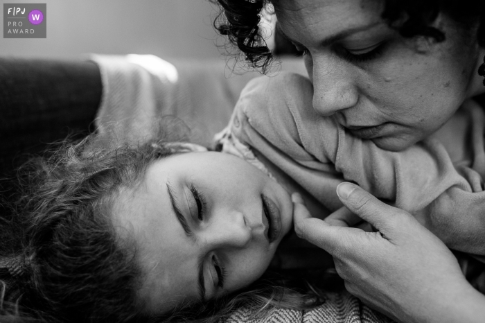 Auvergne-Rhone-Alpes Mom comforts her sick daughter during an in-home family photo session in Savoie