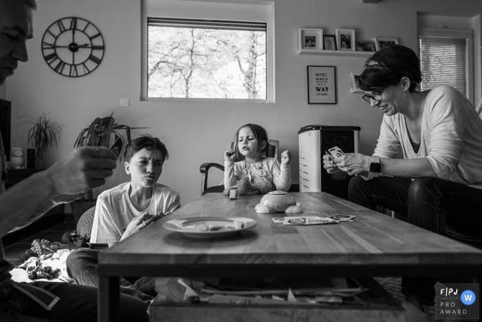 Photo by: <a href="https://www.fpja.com/documentary-family-photography-contests/nadine-court/savoie/2102141">Nadine Court - France</a> Family sits at the table for a game of cards | Savoie Family Sessions