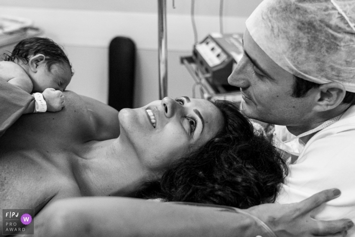 Woman looks to her husband as their newborn child nurses while in the labor room | Rio de Janeiro Birthing