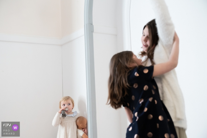 Photo by: <a href="https://www.fpja.com/documentary-family-photography-contests/ralitza-soultanova/brussels/2102244">Ralitza Soultanova - Belgium</a> Little girl with doll watch as the bigger kids play | Belgium Family Photography