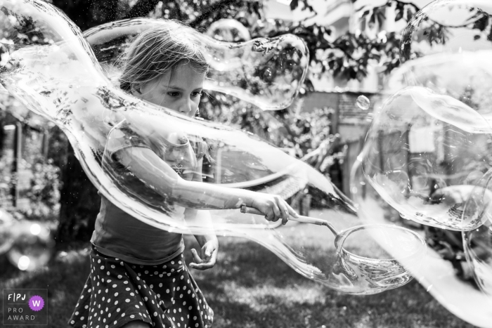 Photo by: <a href="https://www.fpja.com/documentary-family-photography-contests/ralitza-soultanova/brussels/2102246">Ralitza Soultanova - Belgium</a> Girl wrapped in a large, long bubble while playing in the backyard | Brussels Family Photographer