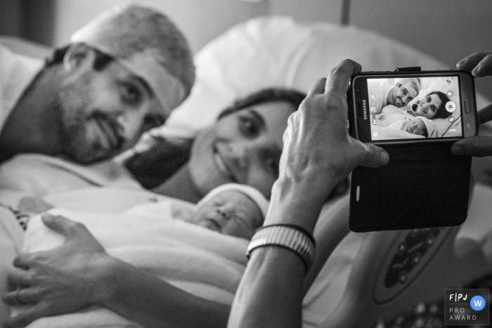 Photo by: <a href="https://www.fpja.com/documentary-family-photography-contests/clara-sampaio/rio-de-janeiro/2102321">Clara Sampaio - Brazil</a> Brazil Hospital Birthing Pro Photographer: When the phone turns into a camera and the joy of the new child's arrival translates into the screen.
