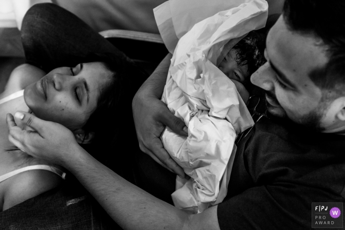 Mother relaxes after giving birth as father holds the new little one | Venezuela Birthing Photography