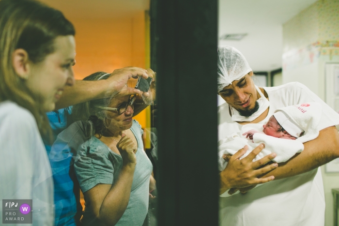 Photo by: <a href="https://www.fpja.com/documentary-family-photography-contests/ana-telma-furtado/rio-de-janeiro/2102357">Ana Telma Furtado - Brazil</a> Photo of father showing the newborn son for the first time to the family and everybody is crying | Brazil birth and family photography