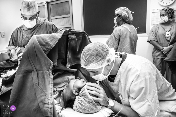 Husband supports his wife as she endures a cesarean | Sao Paulo Birthing Photography