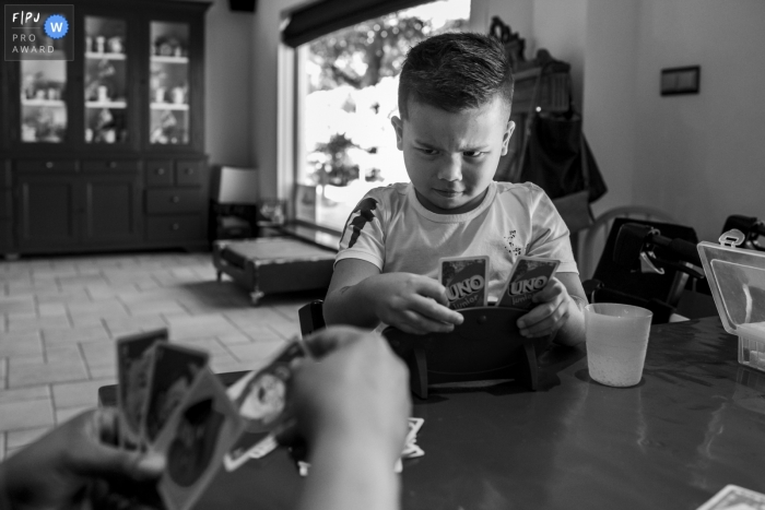 Photo by: <a href="https://www.fpja.com/documentary-family-photography-contests/gonda-meurs/noord-holland/2102462">Gonda Meurs - Netherlands</a> Young boy with a serious face during a game of Uno with the family | Netherlands Family Photo