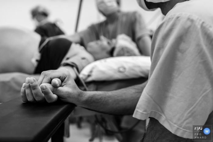 Photo by: <a href="https://www.fpja.com/documentary-family-photography-contests/priscilla-mondo/sao-paulo/2102496">Priscilla Mondo - Brazil</a> Brazil husband holding hands during birthing - by your side photography