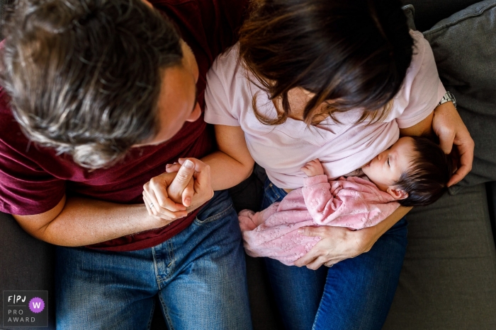 Family sits on a sofa as infant nurses | Sao Paulo Family Photography