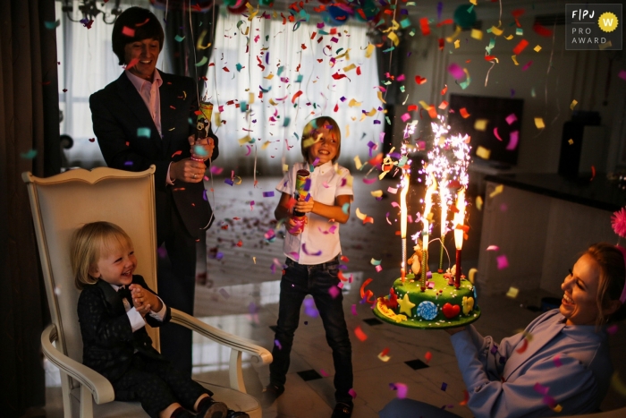 Family celebrates a birthday with a sparkler-lit cake and confetti | Russia party photography 