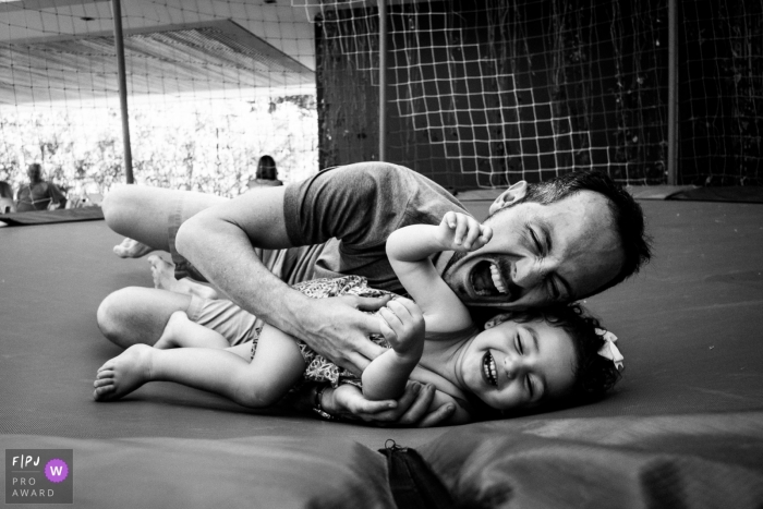 Photo by: <a href="https://www.fpja.com/documentary-family-photography-contests/joni-pereira/florianopolis/2102662">Joni Pereira - Brazil</a> A playful father plays with his daughter in a trampoline | Brazil family photographer